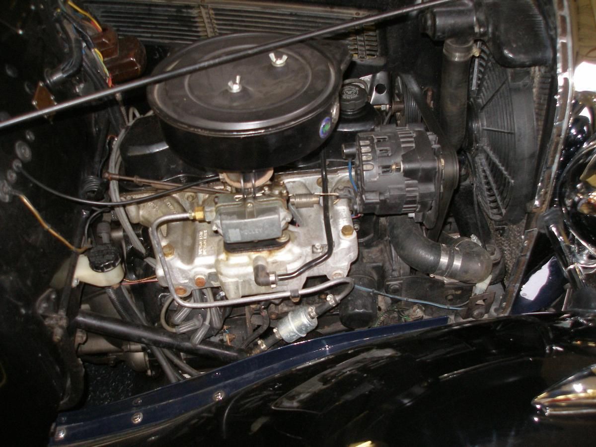 A close up of a car engine with a carburetor