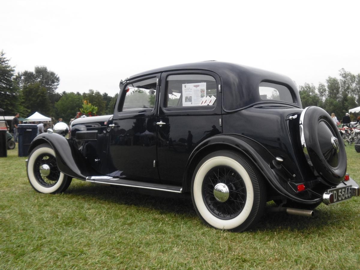 A black car with white tires is parked in the grass