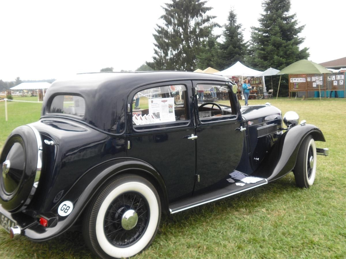 A black car with white tires is parked in a grassy field