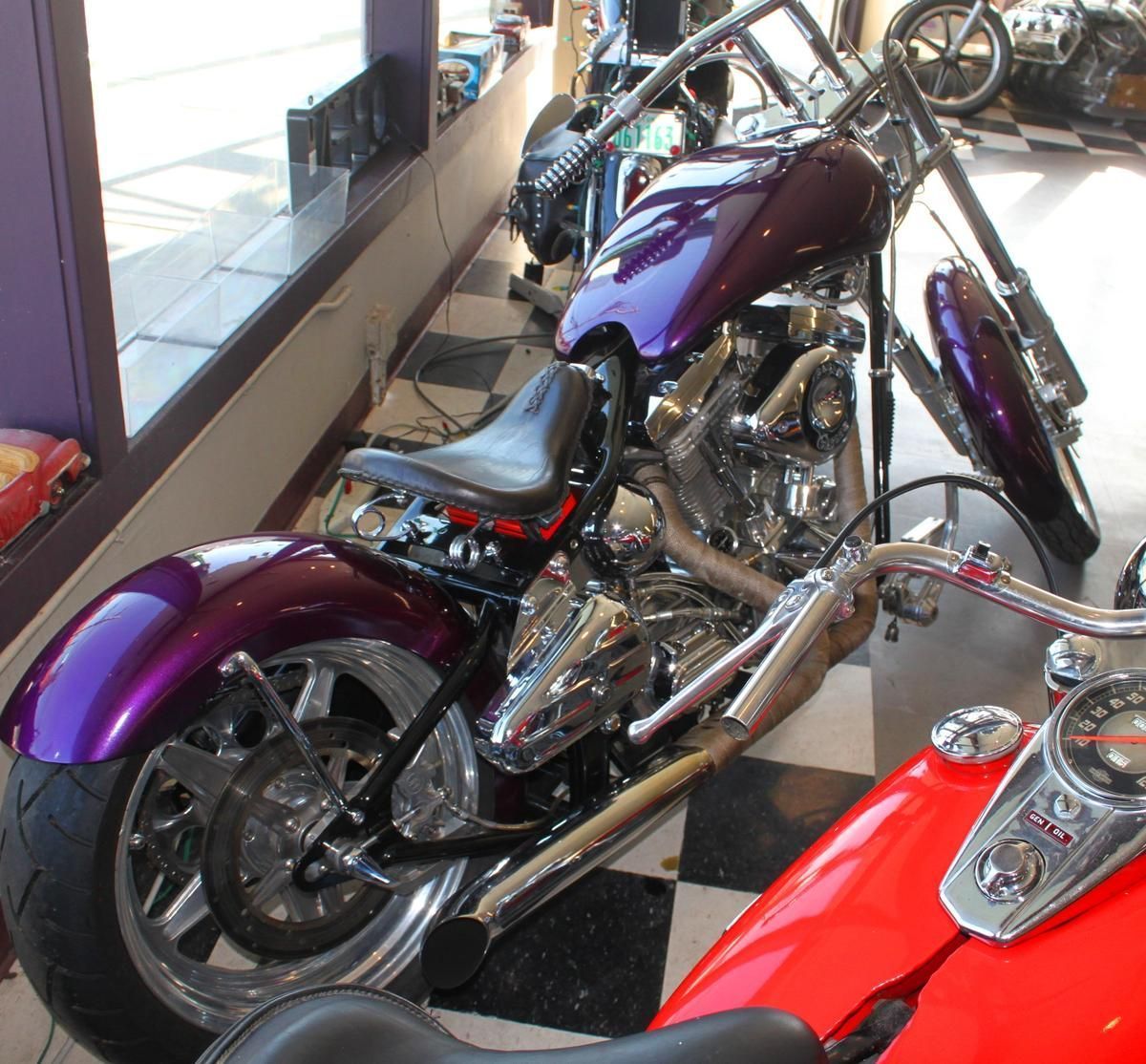 A purple motorcycle is parked next to a red motorcycle