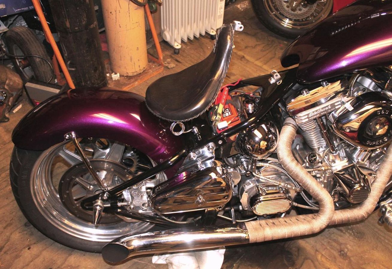 A purple motorcycle with a black seat is parked in a garage