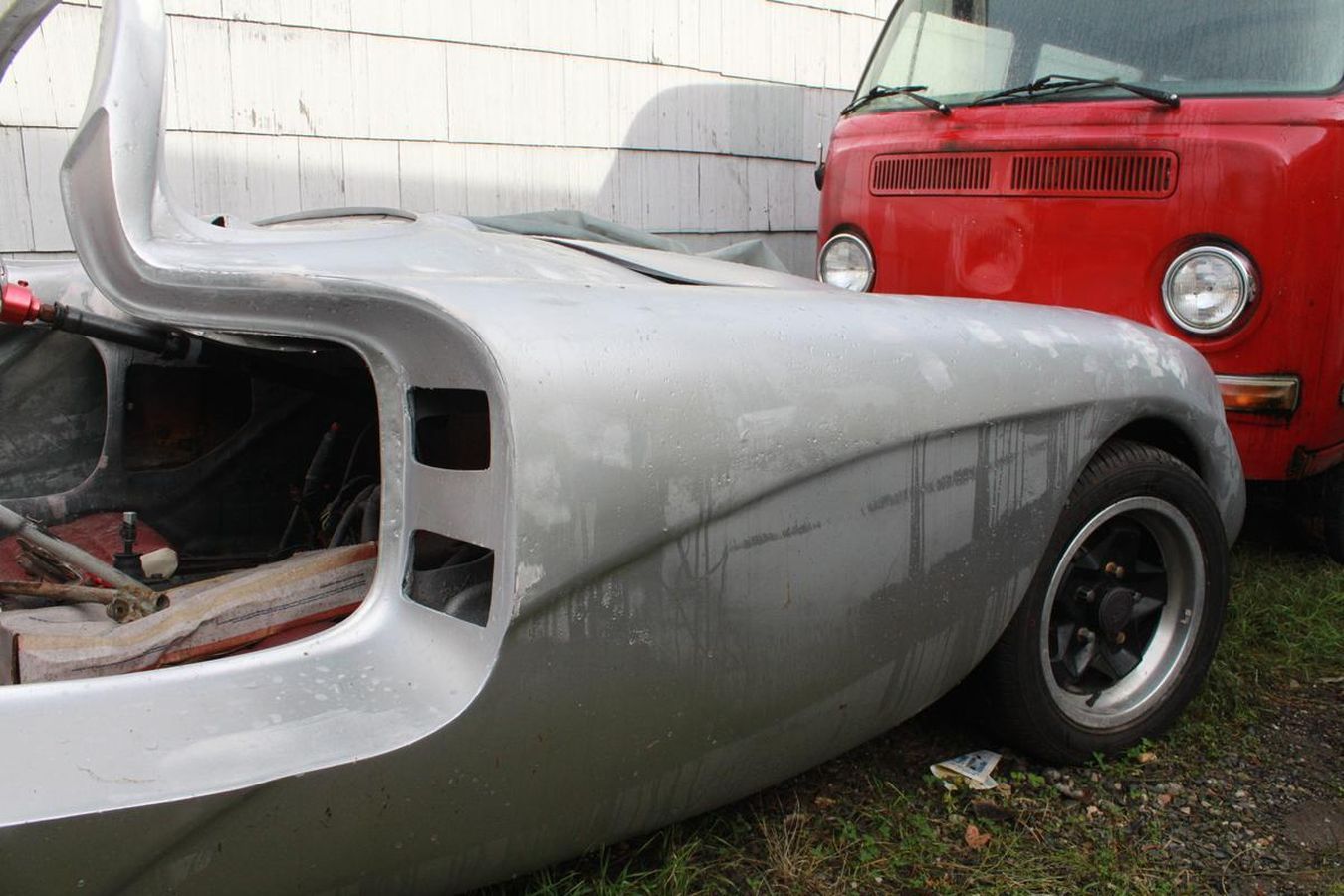 A silver car is parked next to a red truck