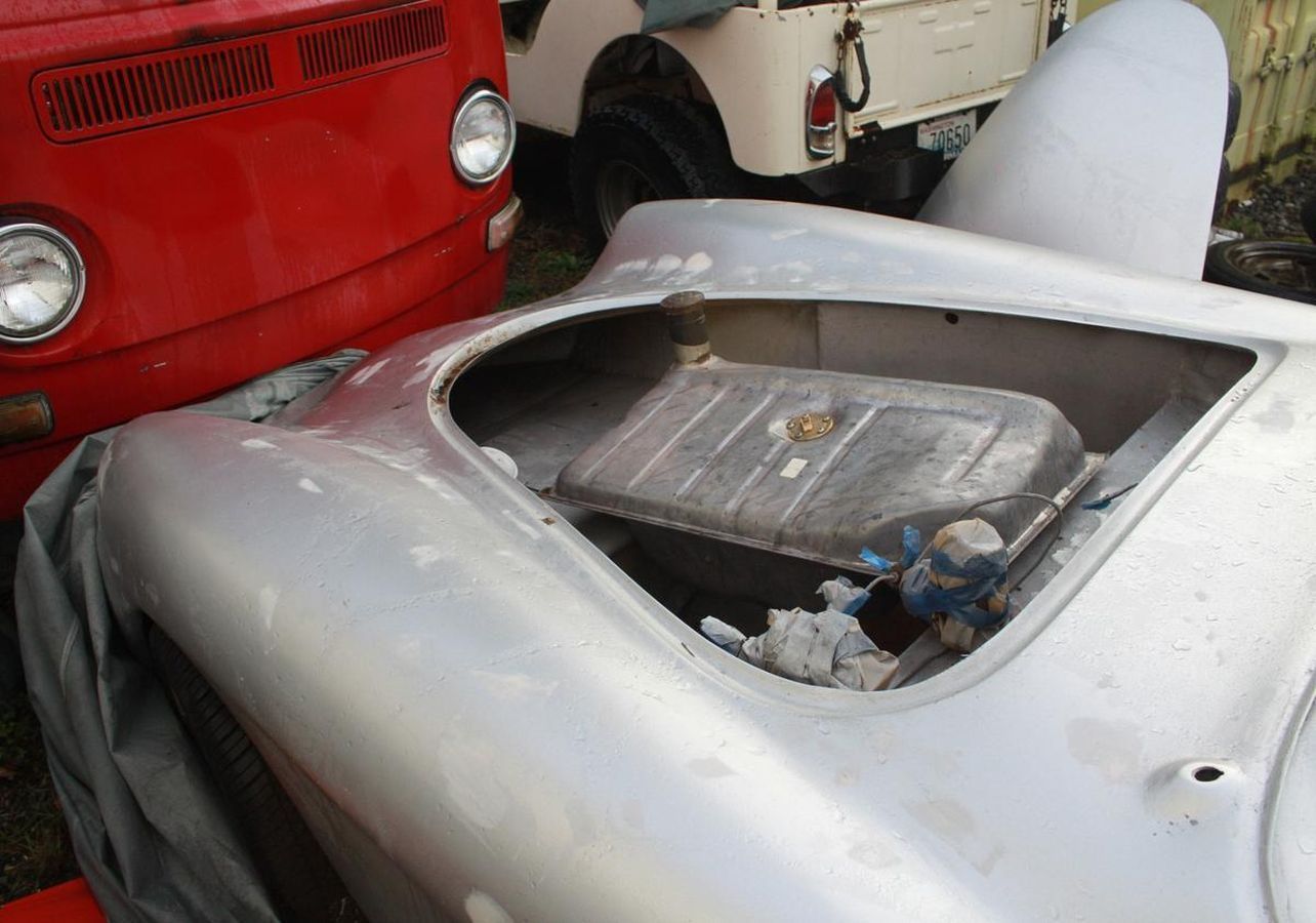 A silver car with a fuel tank in the trunk