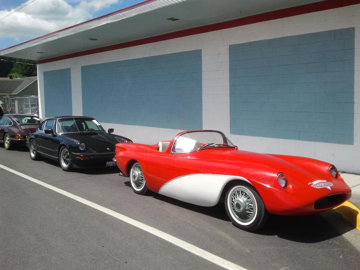 A red and white sports car is parked in front of a building