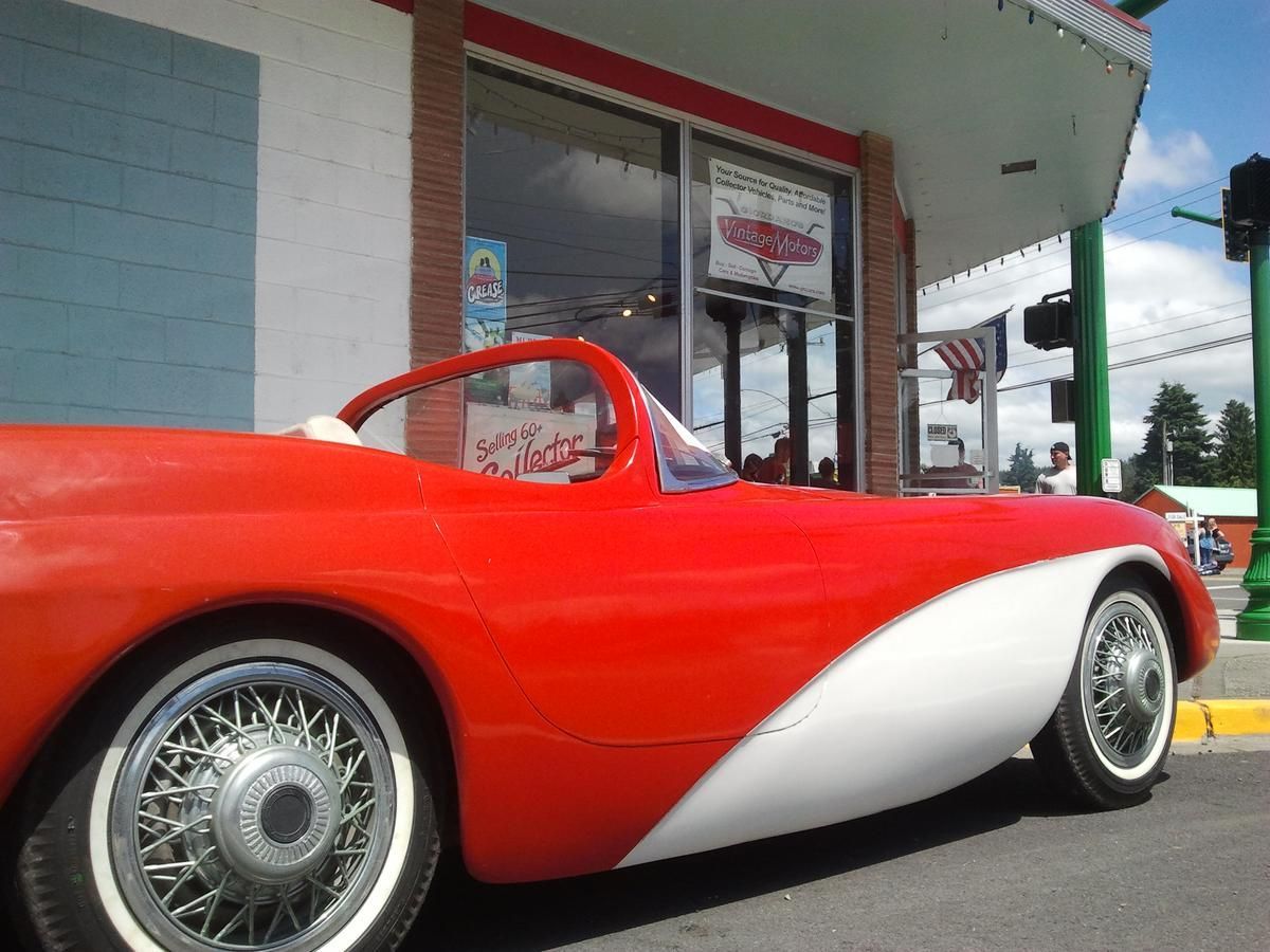 A red and white sports car is parked in front of a restaurant