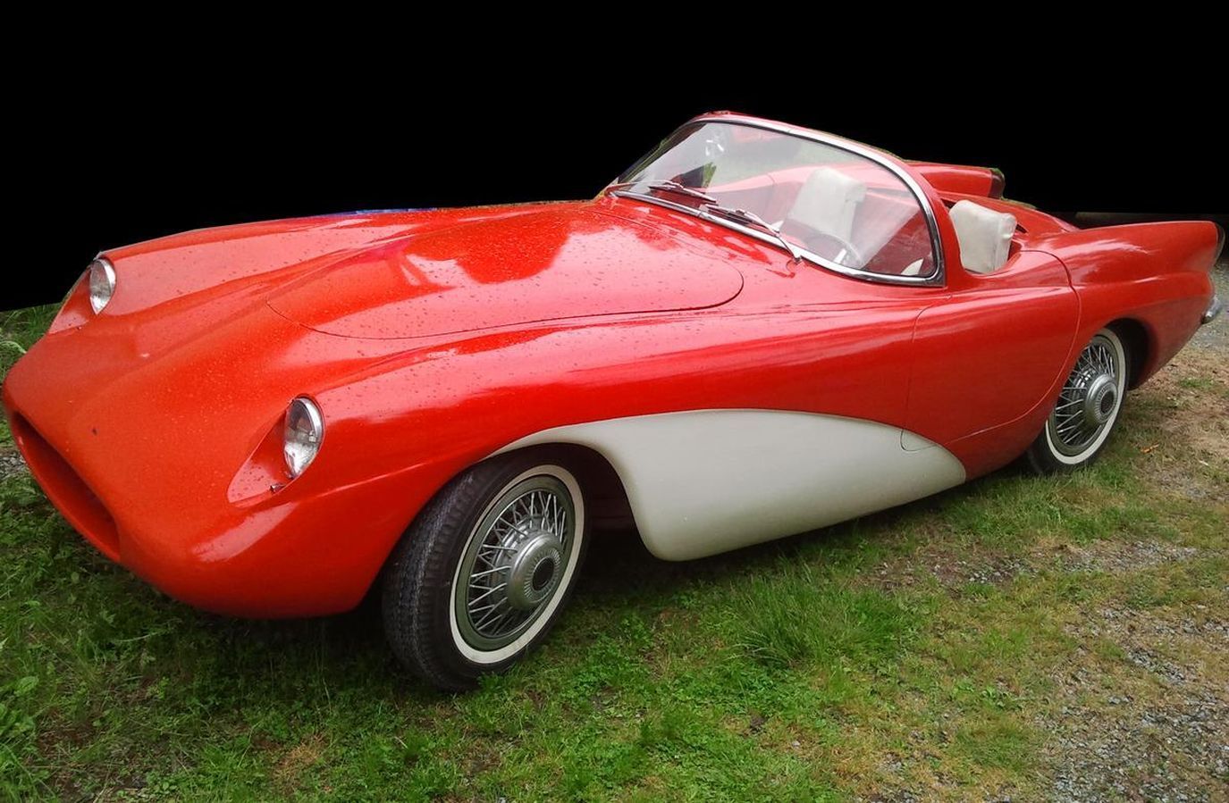 A red and white sports car is parked in the grass