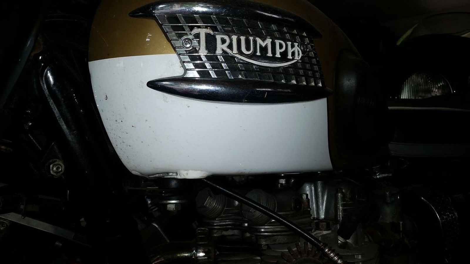 A triumph motorcycle is parked in a dark room.