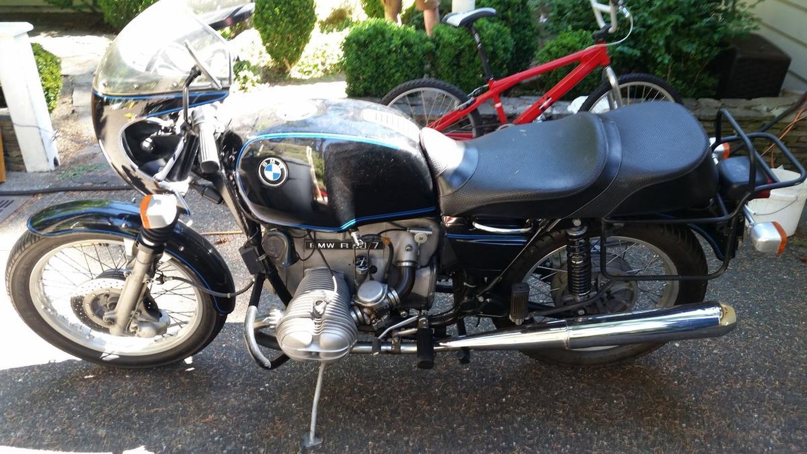 A black bmw motorcycle is parked next to a red bicycle.