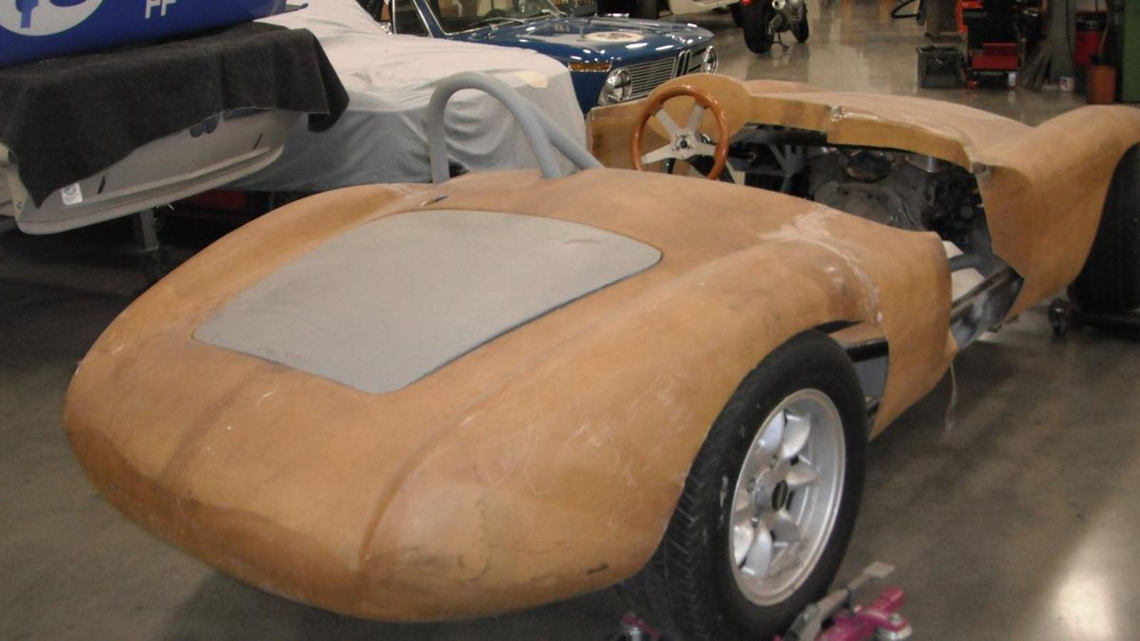 A model car is sitting on a concrete floor in a garage.