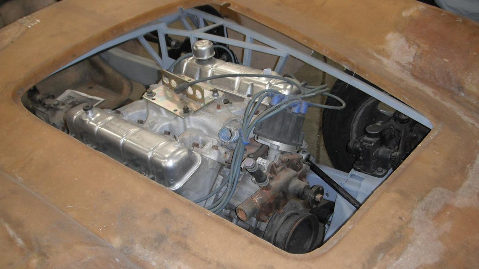 A car engine is sitting in the trunk of a car.