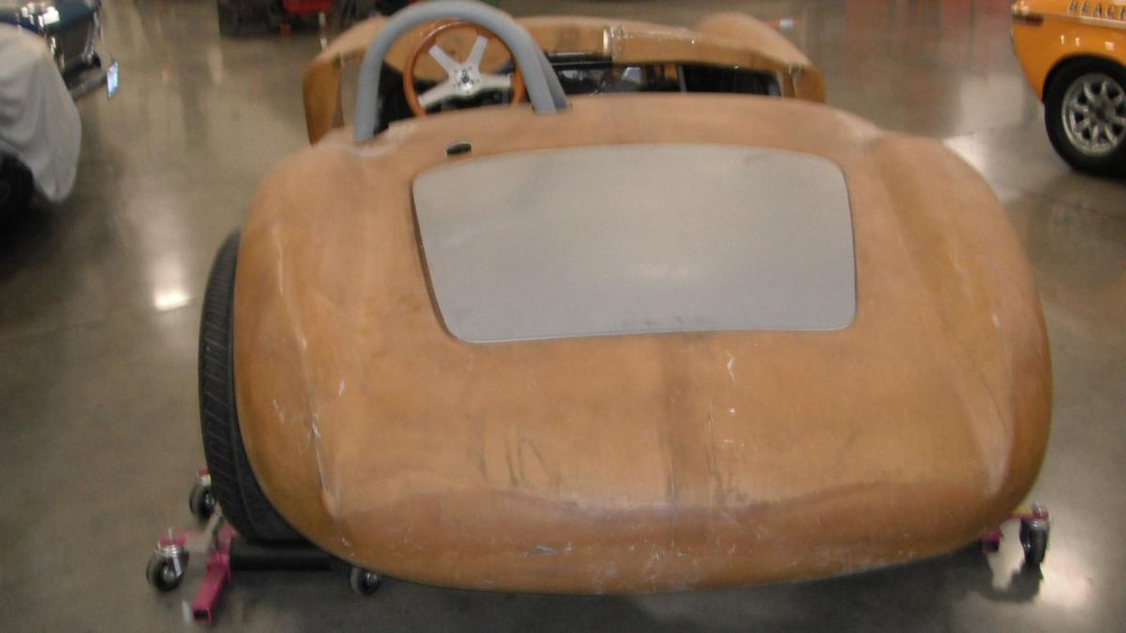 A brown car is sitting on wheels in a garage