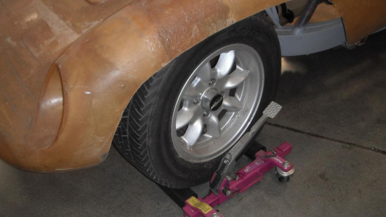 A car wheel is sitting on a pink jack.