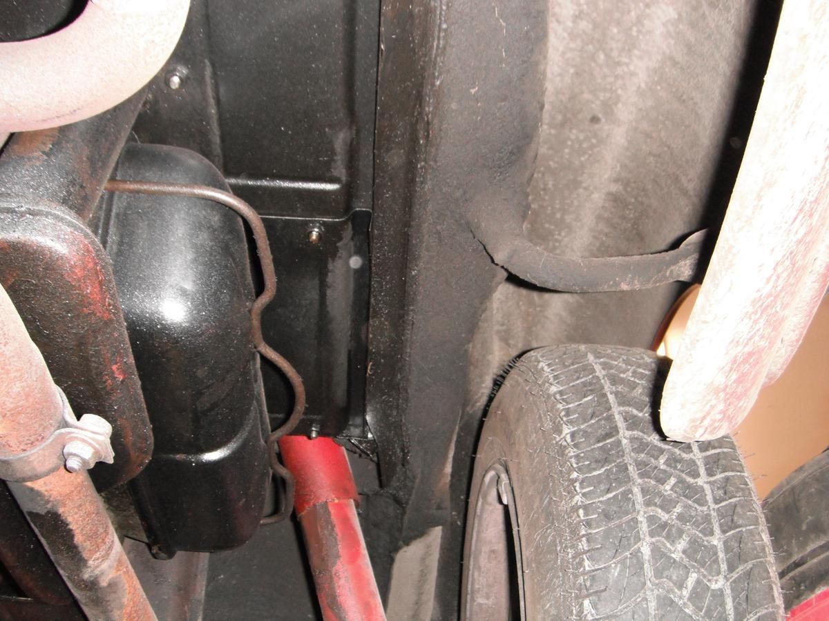 A close up of the underside of a car with a tire in the foreground