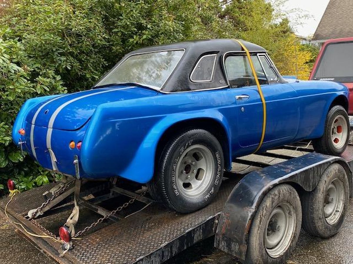 A blue car is sitting on top of a trailer.