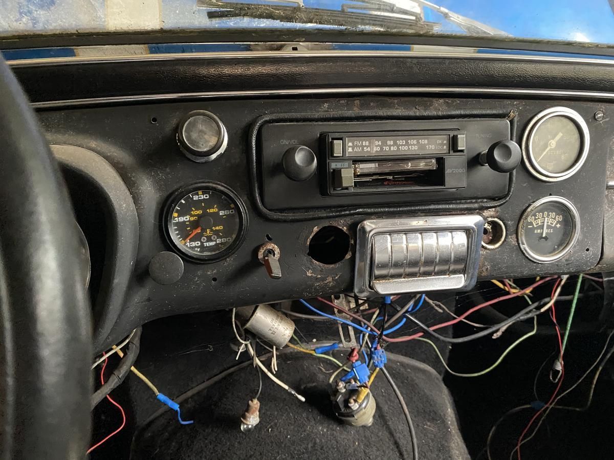 The dashboard of an old car has a lot of wires coming out of it