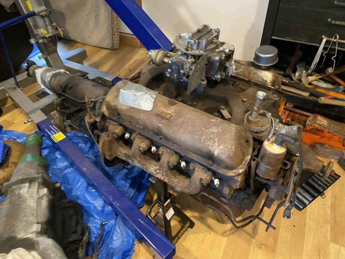 An old engine is sitting on top of a blue tarp on a wooden floor.