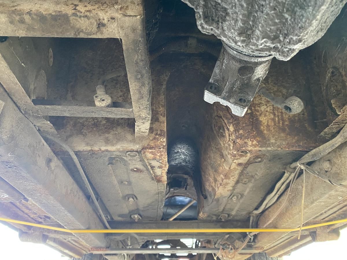 A close up of the underside of a car with a yellow measuring tape.