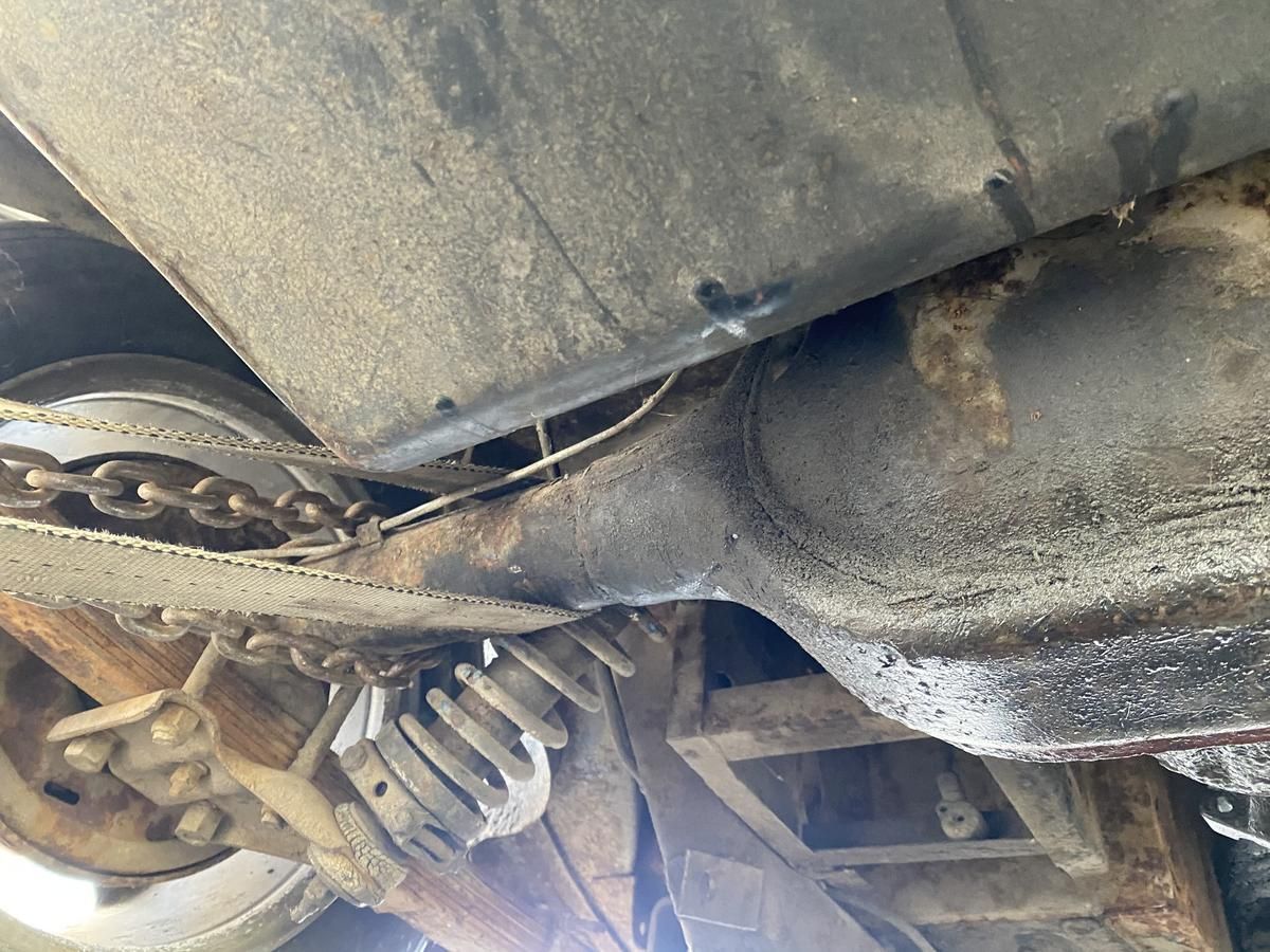 A close up of the underside of a car with a chain hanging off of it.