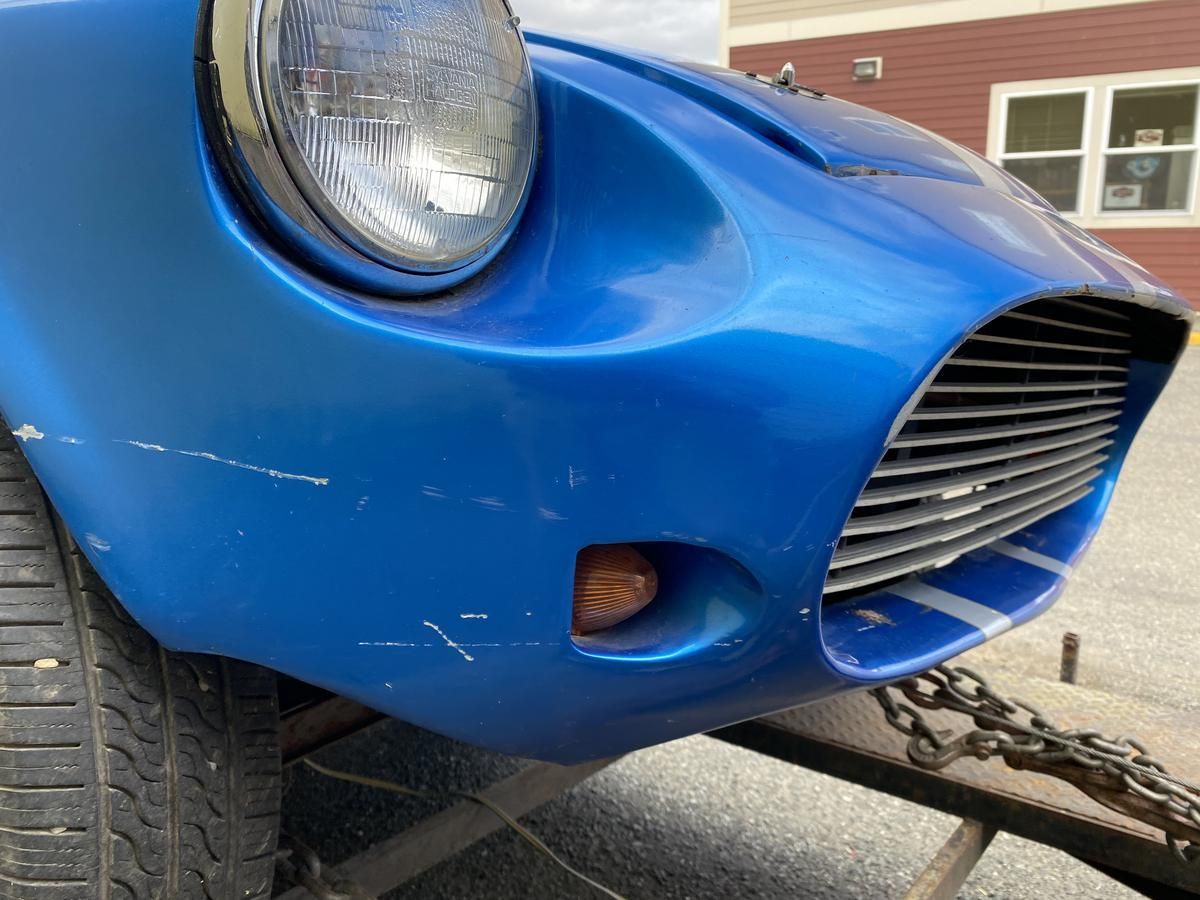 A blue car is being towed by a trailer