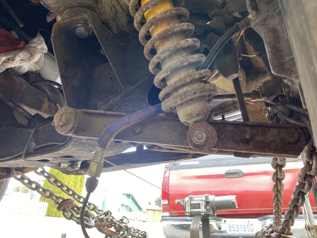 A red truck is parked behind a car that is being worked on.