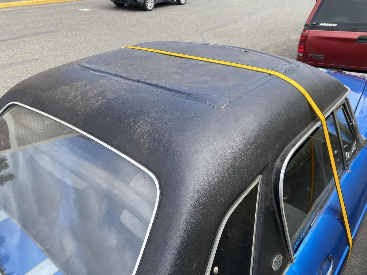 The roof of a blue car is tied with a yellow rope