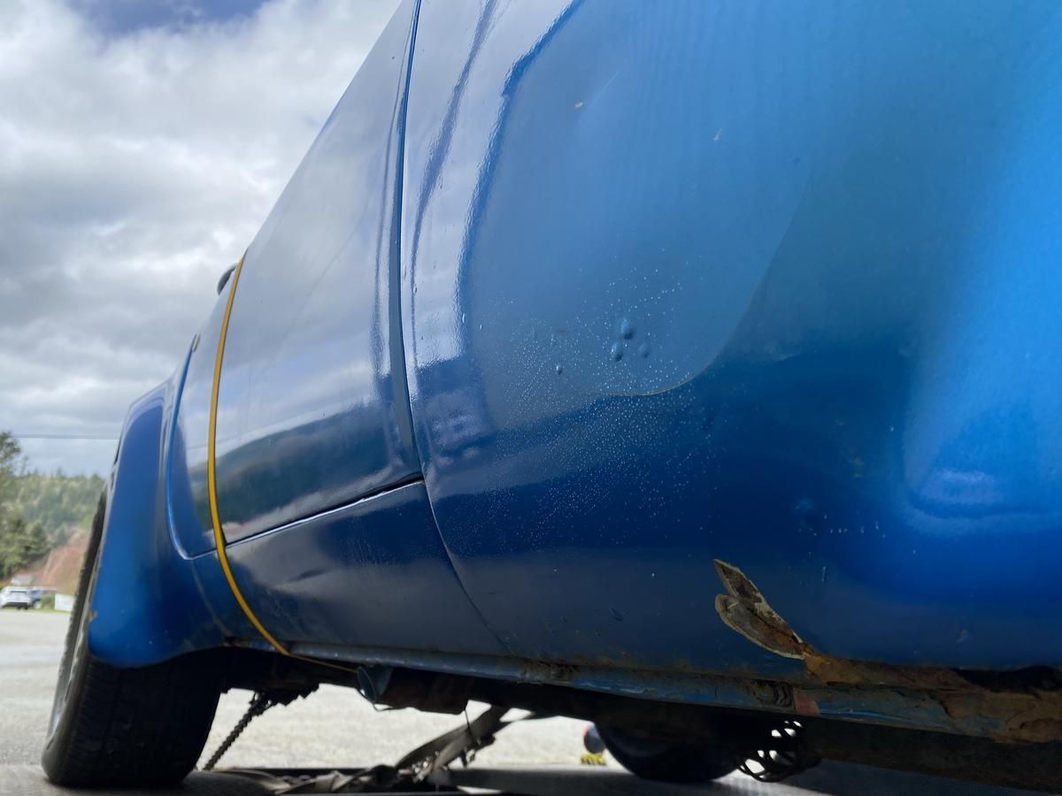 A blue truck is parked on the side of the road.