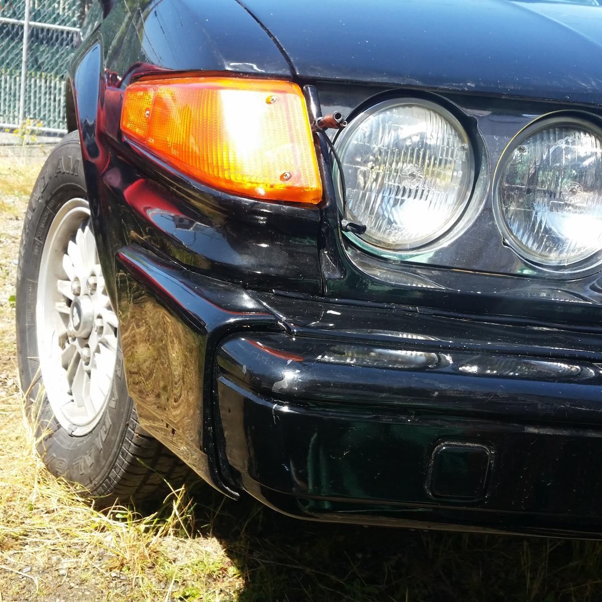 A close up of a black car 's headlight and bumper