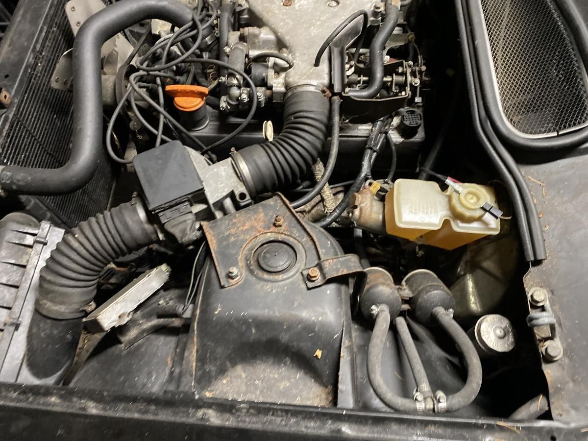 A close up of a car engine with a hose coming out of it