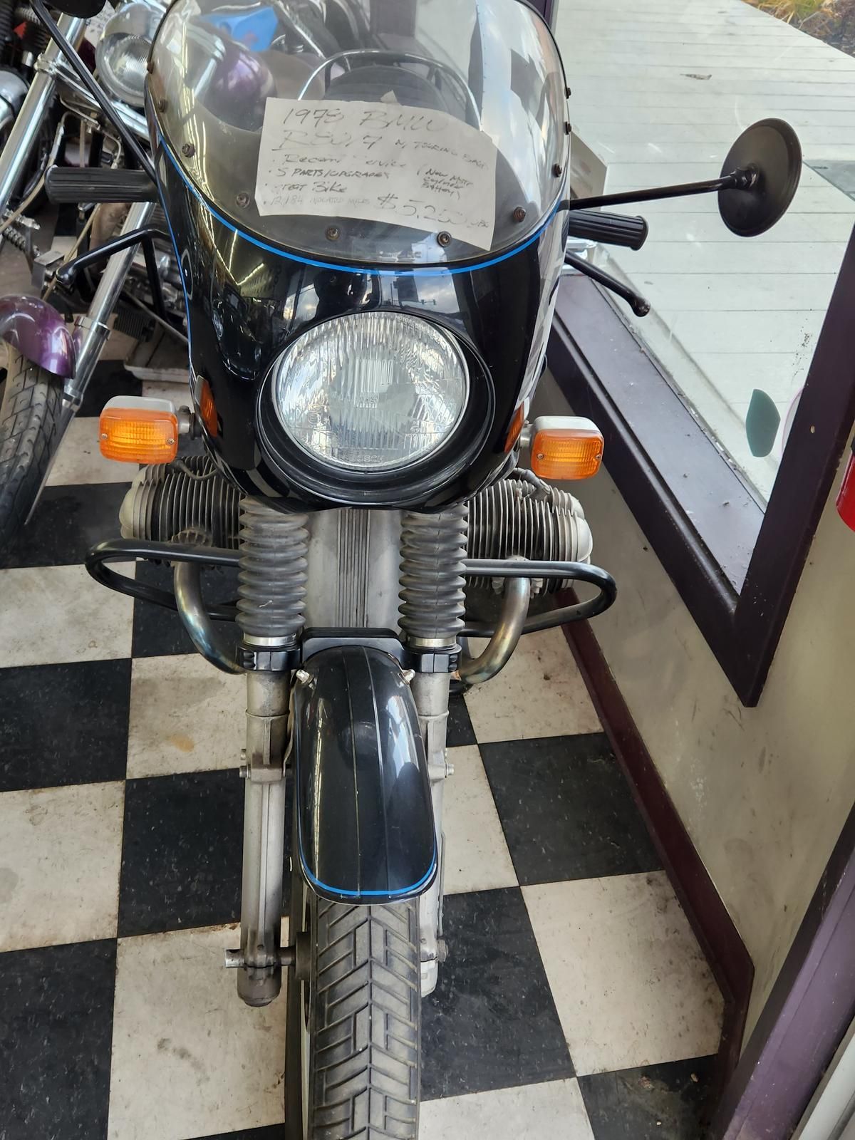 A black motorcycle is parked in a room with a checkered floor