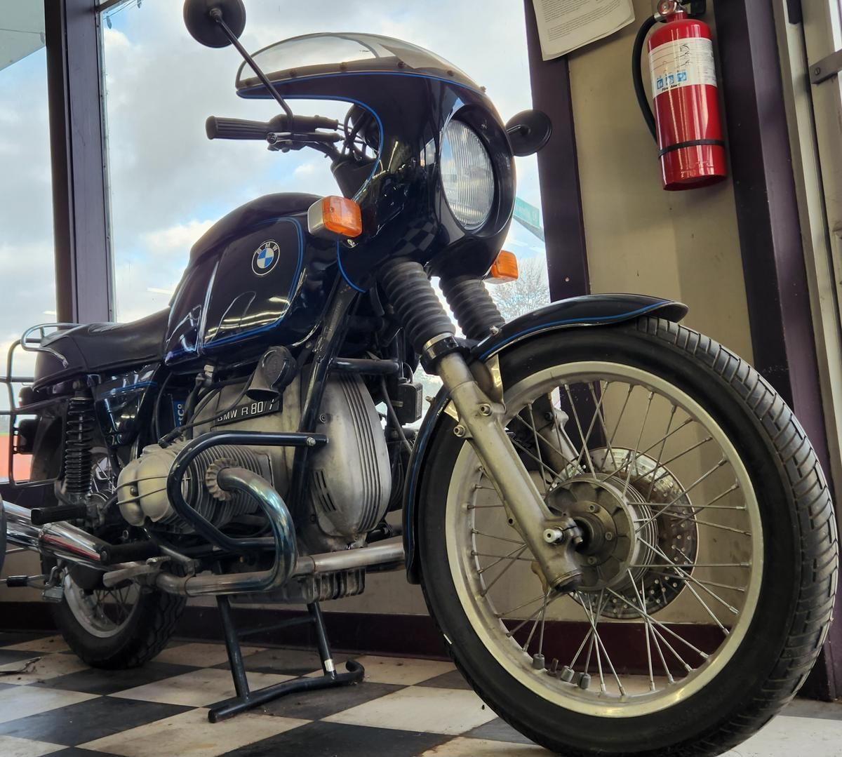 A motorcycle is parked in front of a fire extinguisher