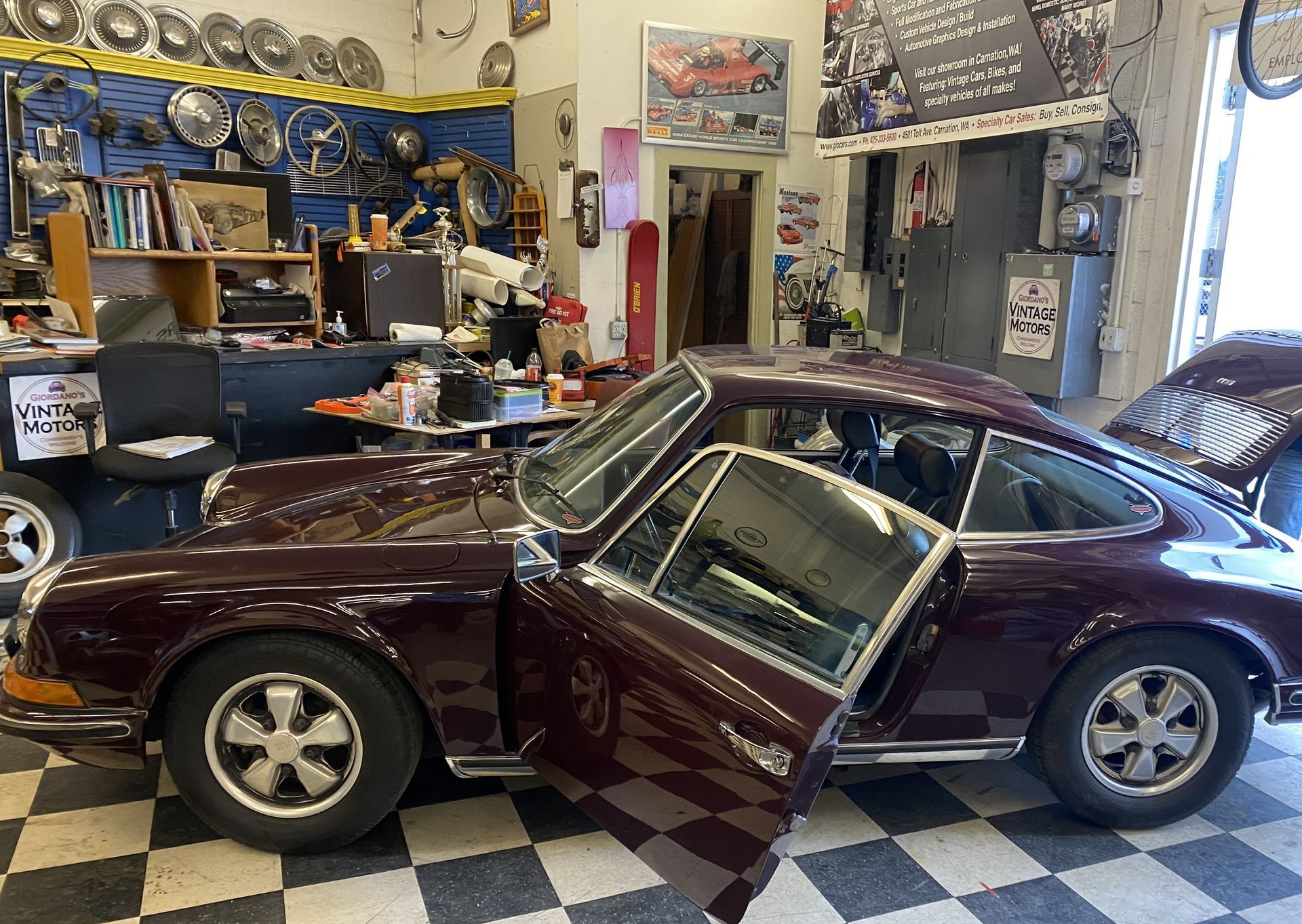 A purple car is parked in a garage with its doors open