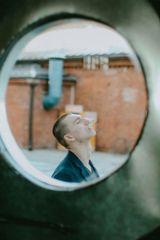 A man is looking up through a round window.