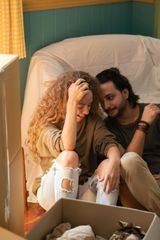 A man and a woman are sitting on a couch next to a box.