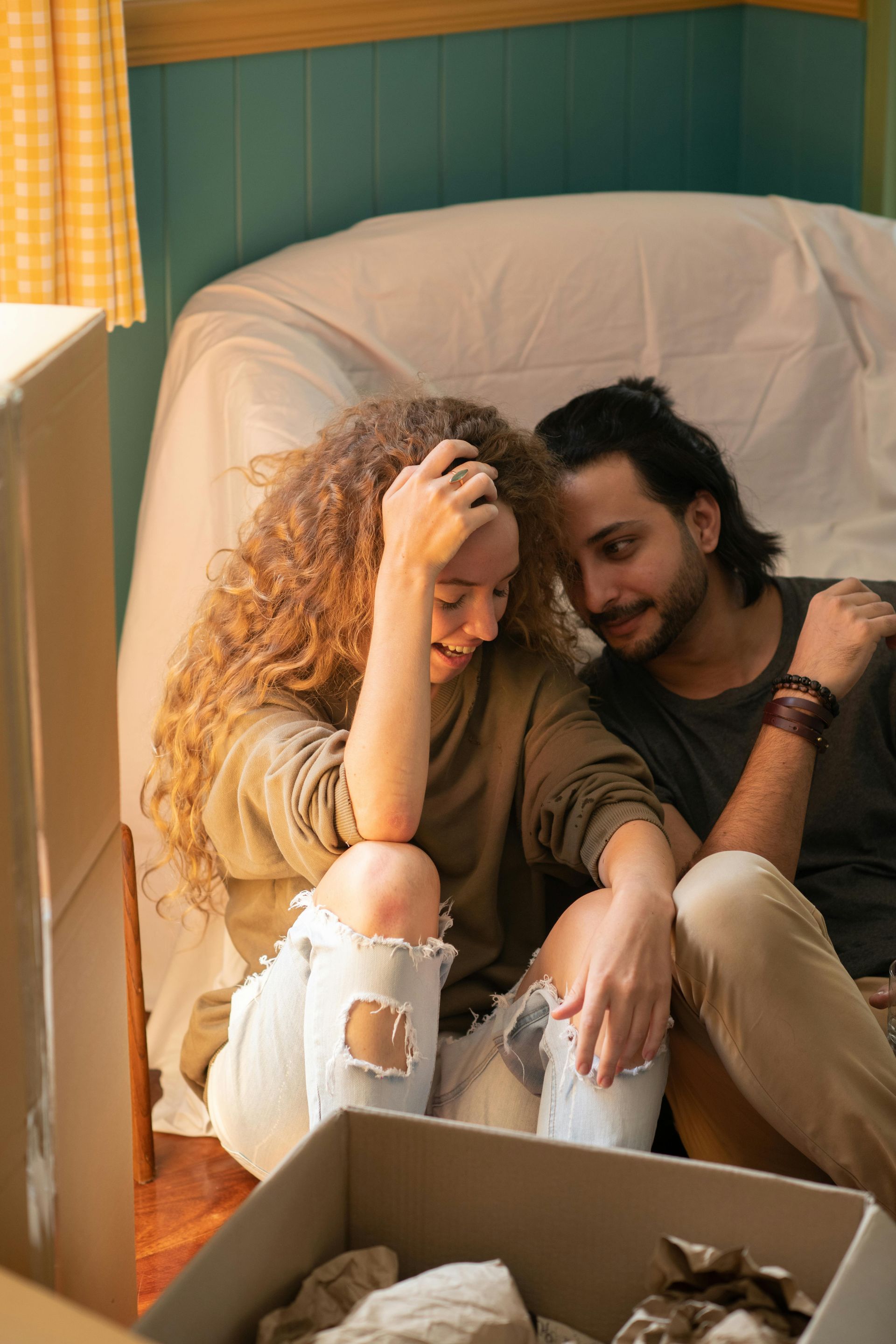 A man and a woman are sitting on a couch next to a box.