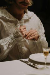 A man is sitting at a table holding a glass of wine.