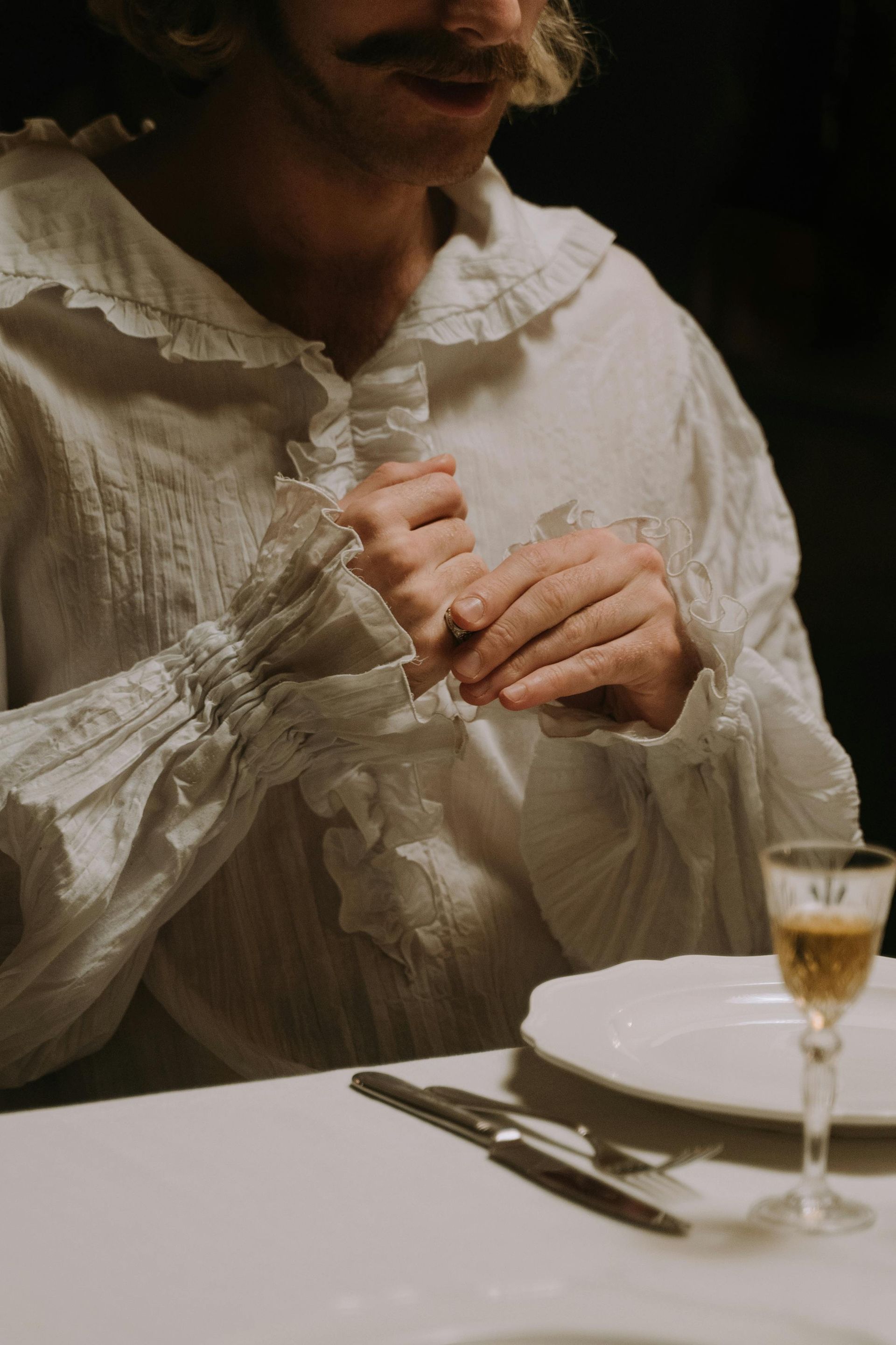 A man is sitting at a table holding a glass of wine.