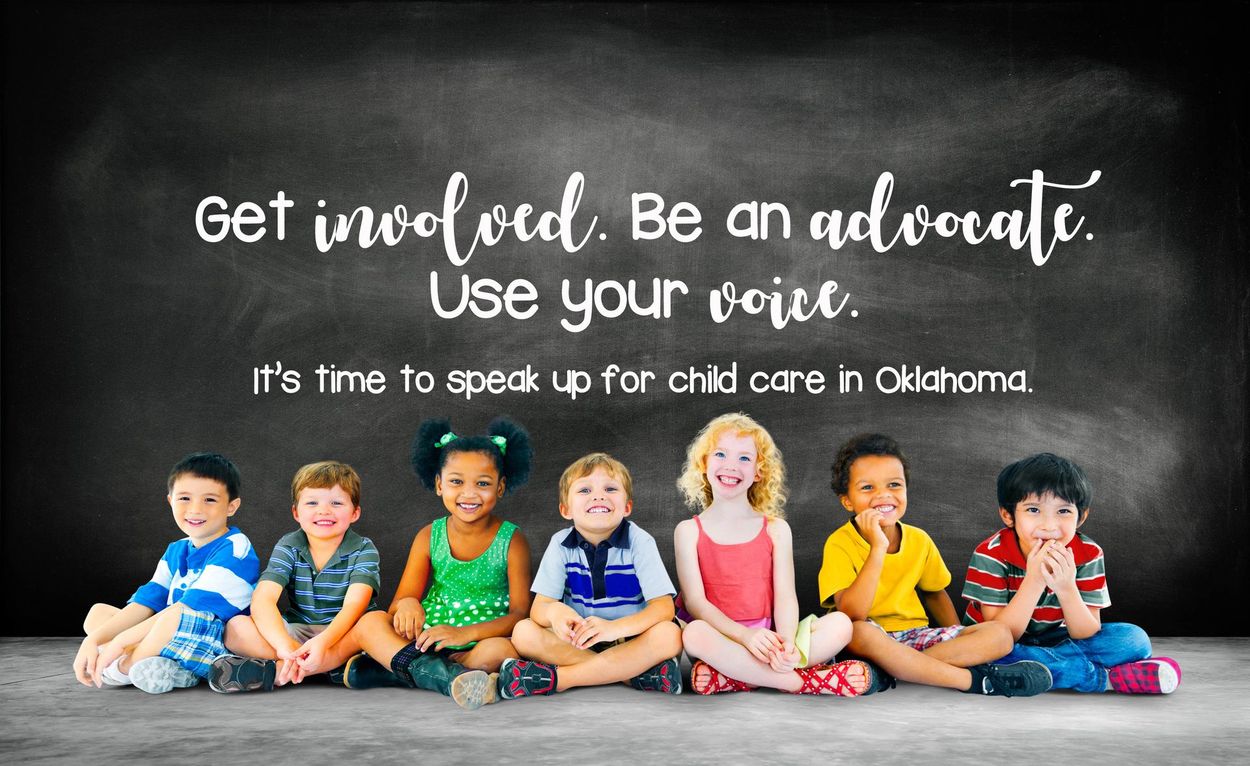 A group of children are sitting on the floor in front of a blackboard.