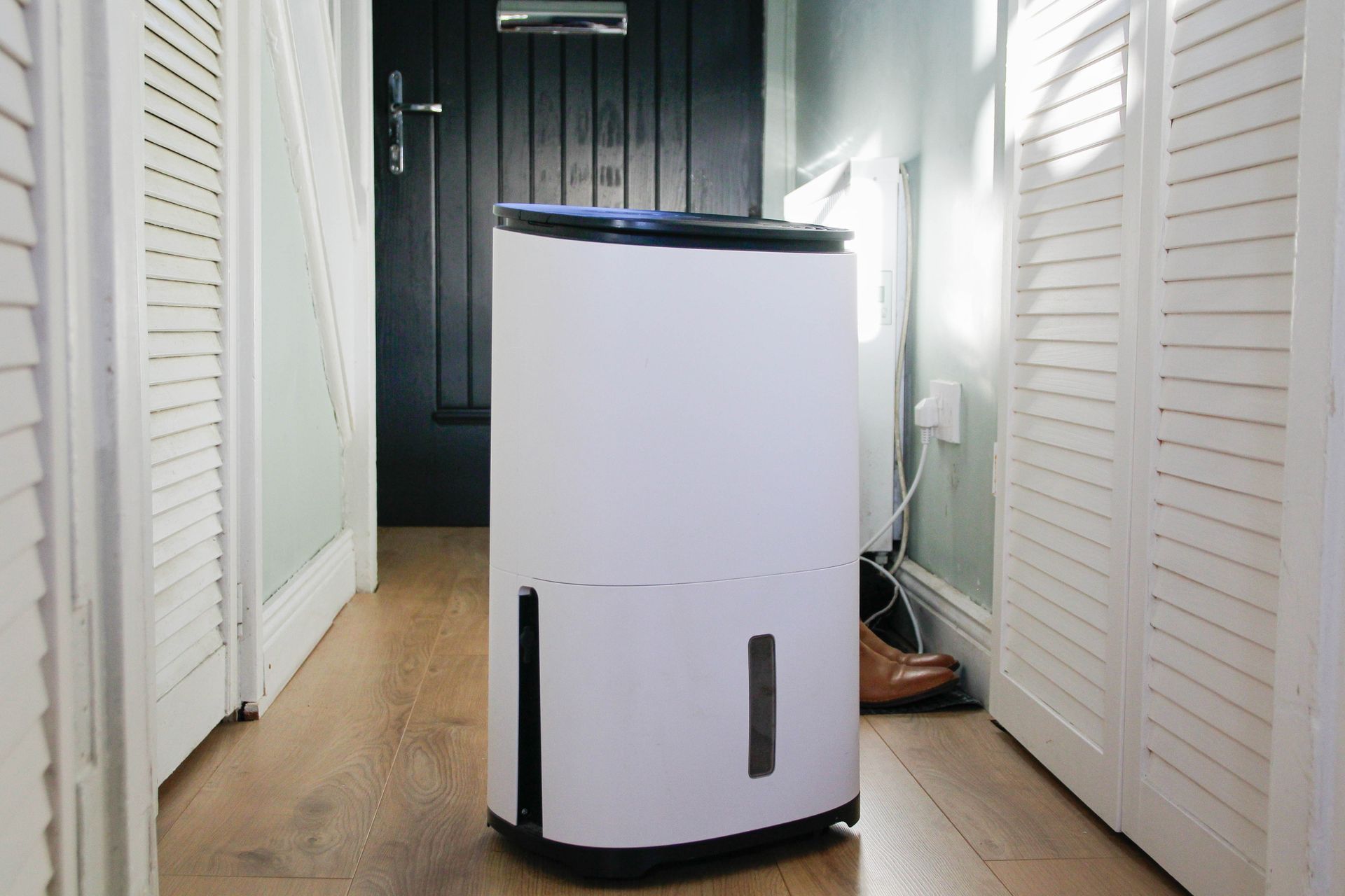 A white air purifier is sitting in a hallway next to a door