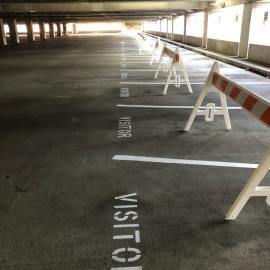A row of white and orange barricades blocking parking spaces marked 