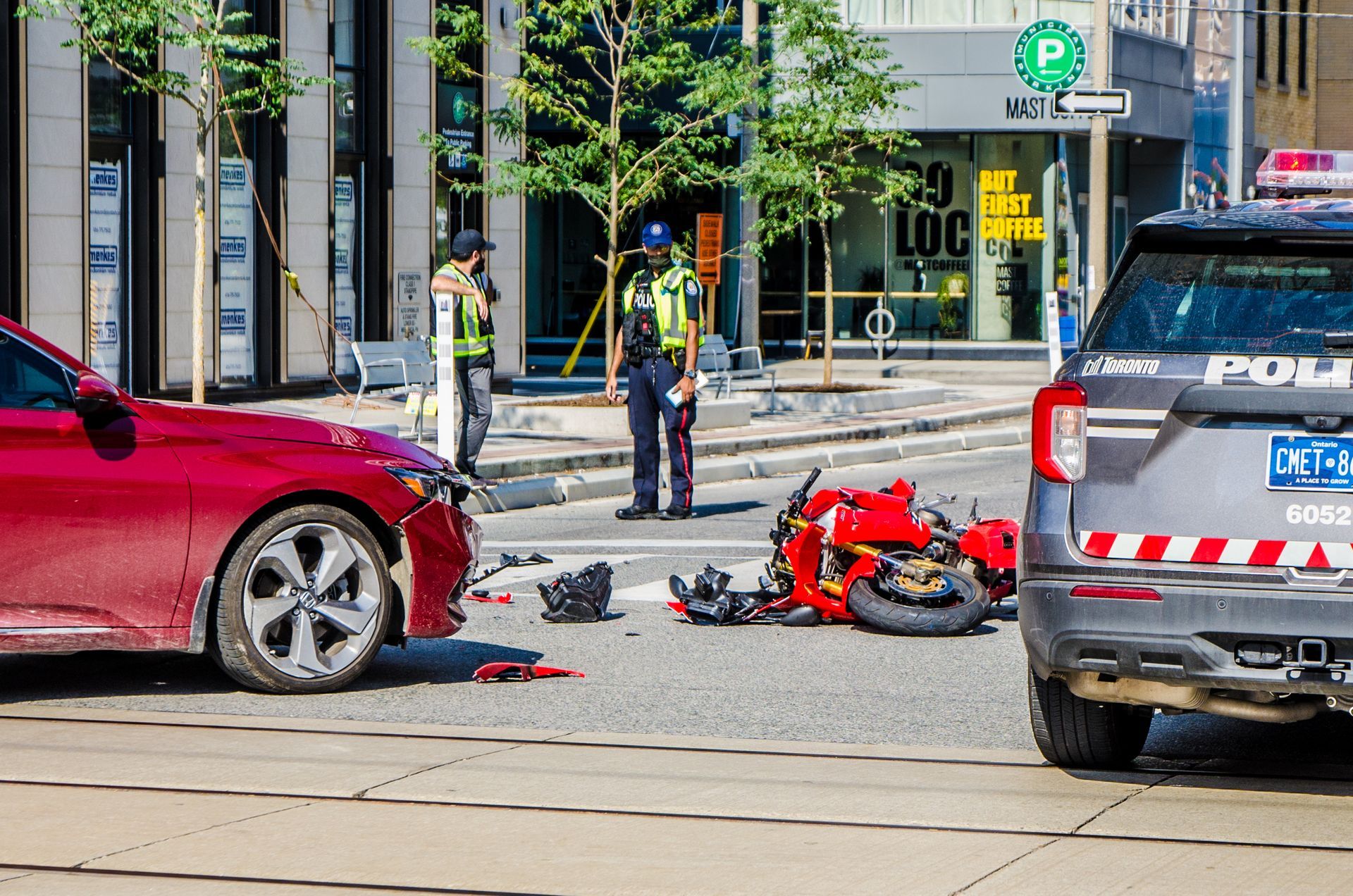 A motorcycle is laying on the side of the road next to a car.