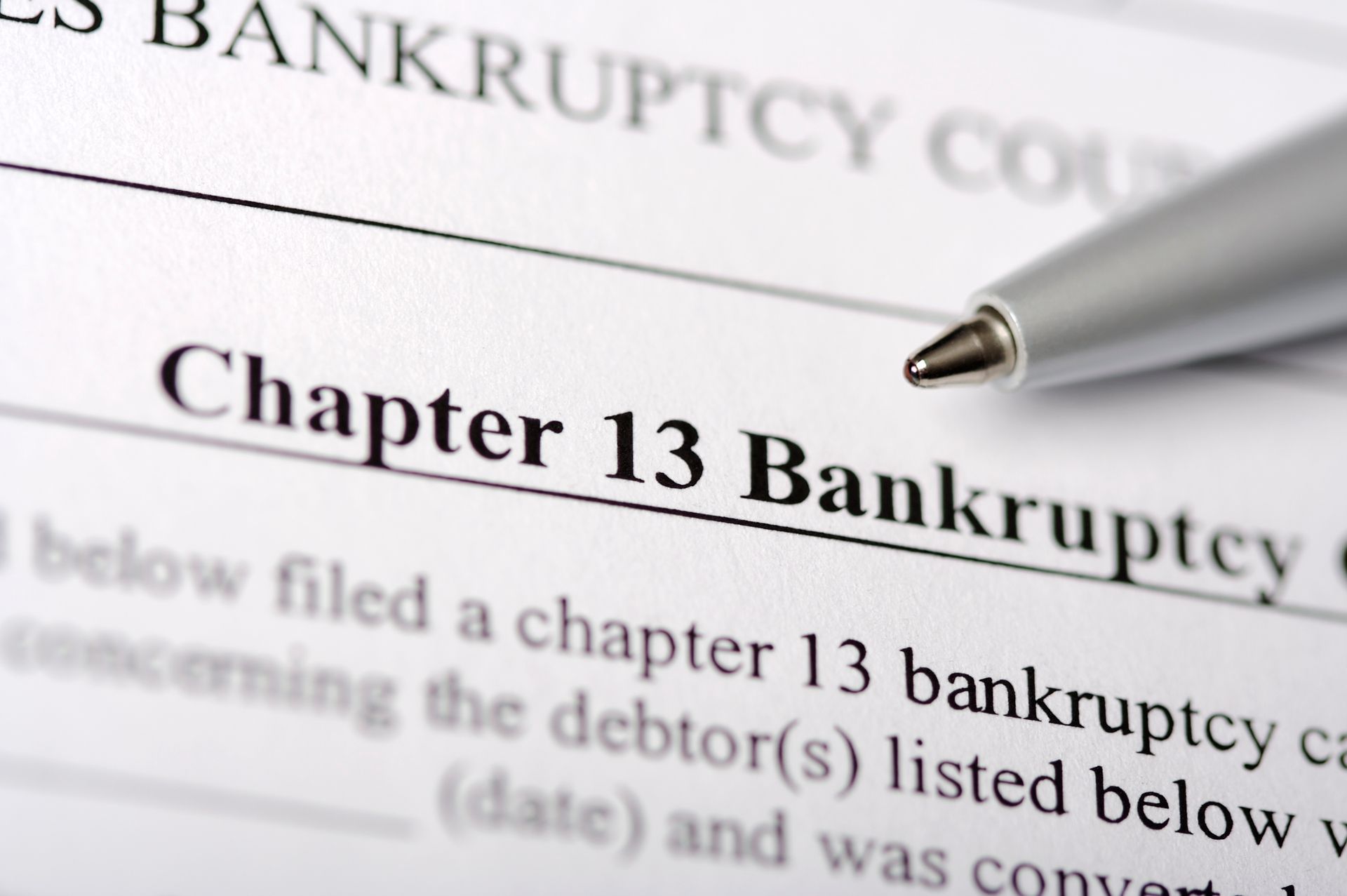 A pen rests on a piece of paper that says chapter 13 bankruptcy