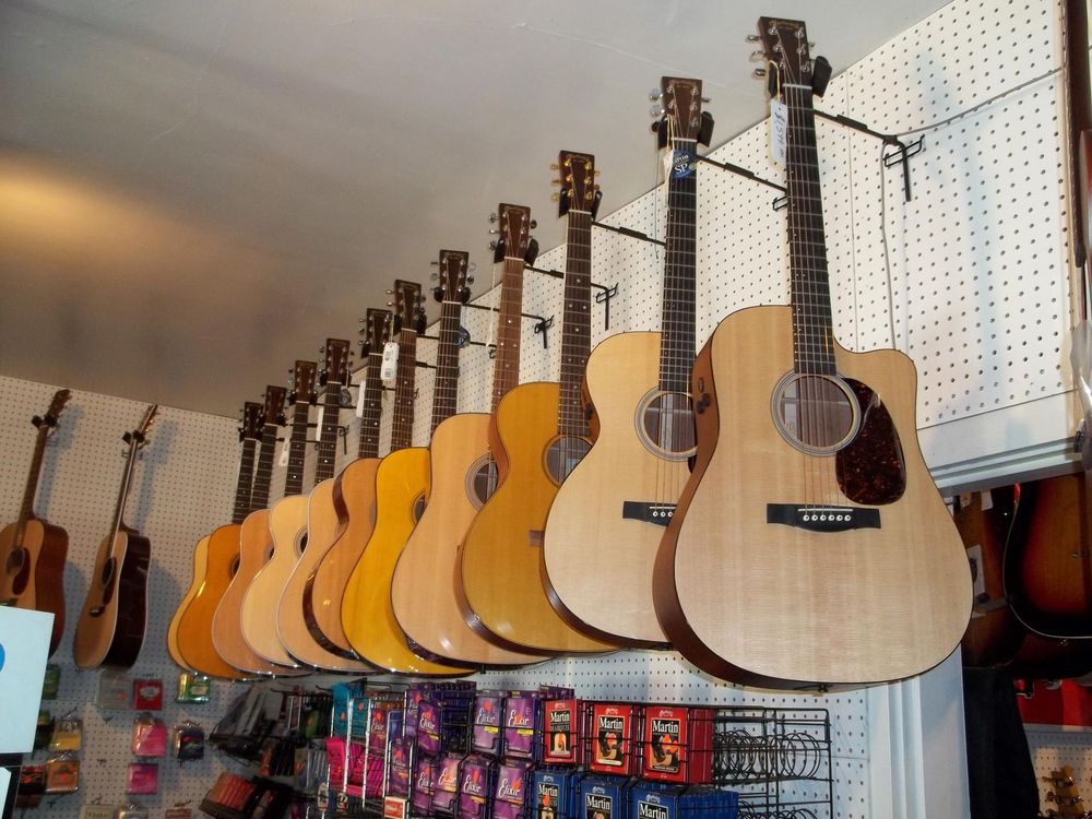 Guitars hanging on a store wall, with rows of colorful accessories below.