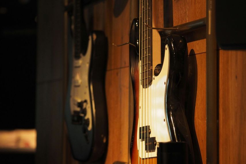 Guitars hanging on a wooden wall, with a dark electric guitar in the foreground.