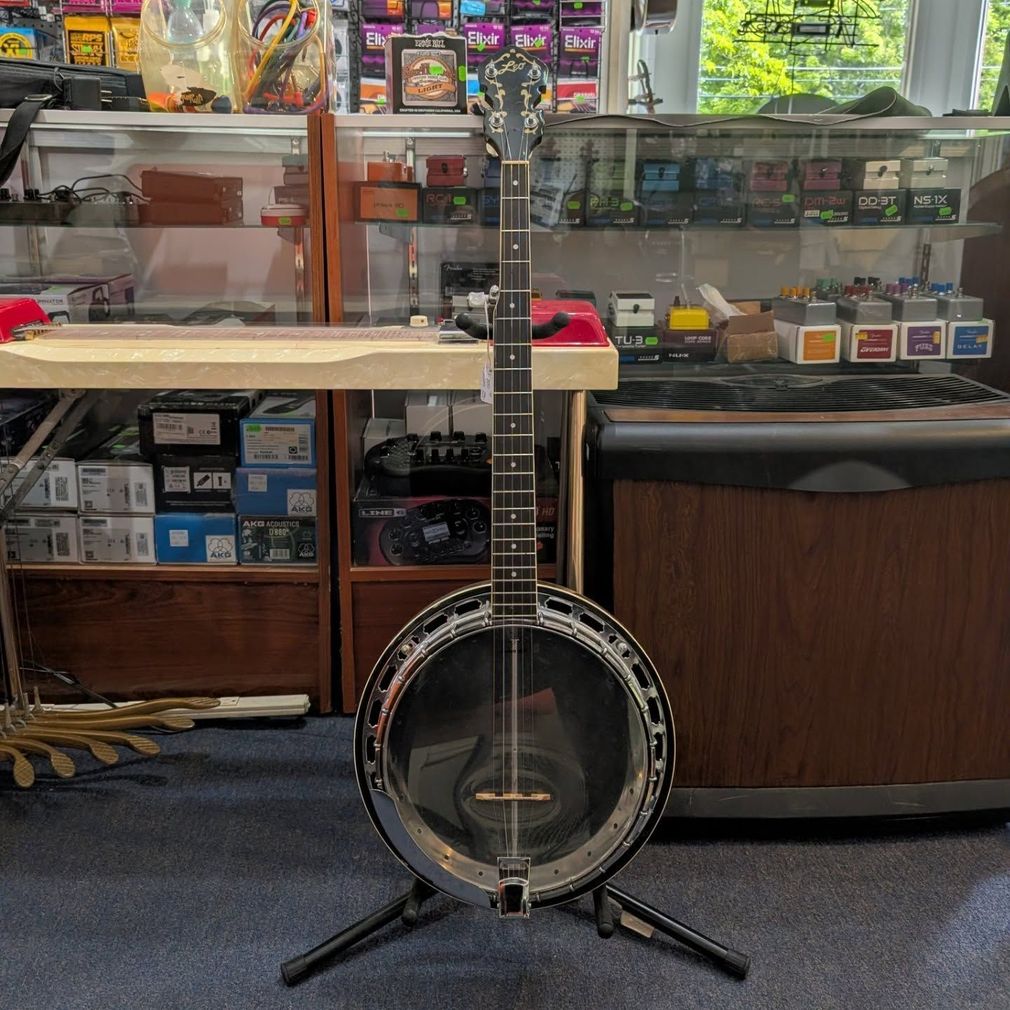 Banjo on a stand in a music store, with glass display cases and instruments behind it