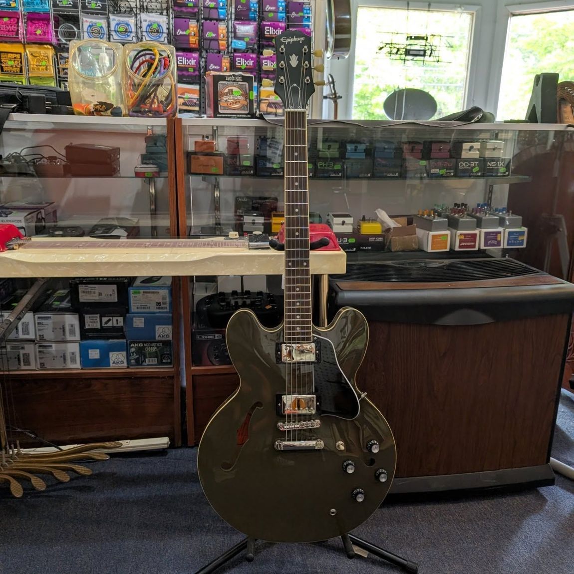 Dark electric guitar standing in a shop in front of glass display cases of accessories.