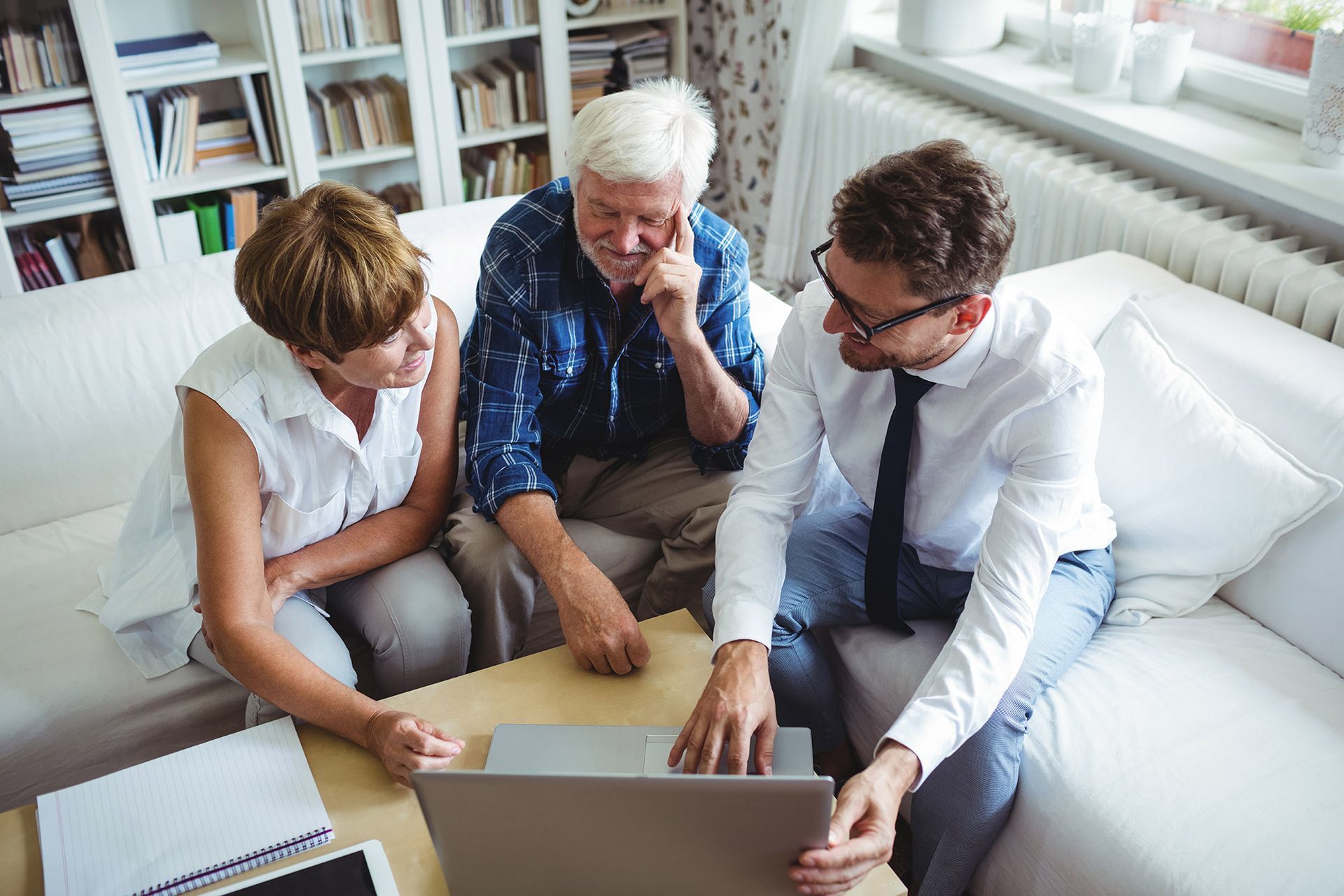 Couple reviewing laptop with advisor on couch.