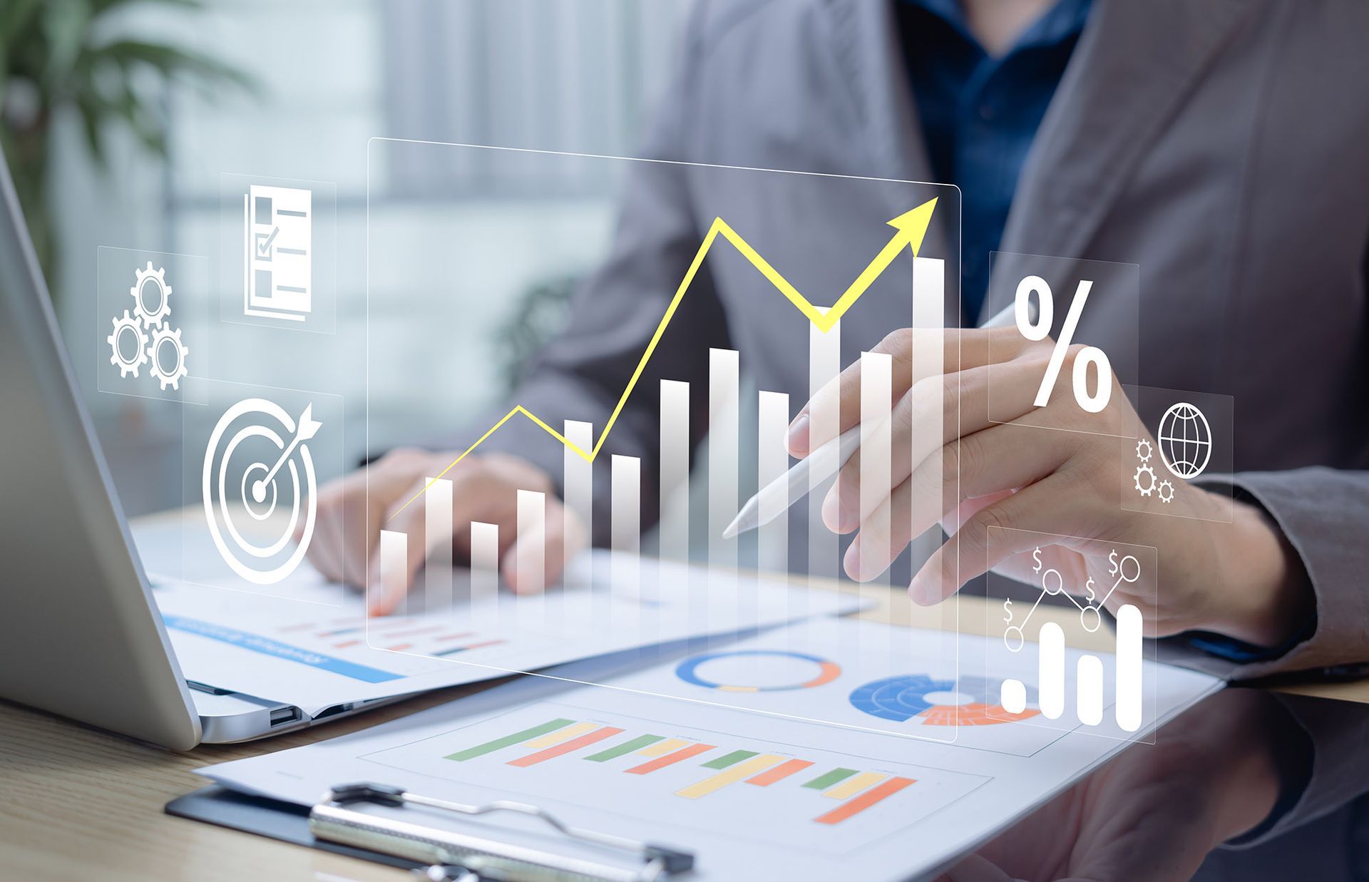 Person analyzes financial data, graphs and charts, with a laptop and pen.