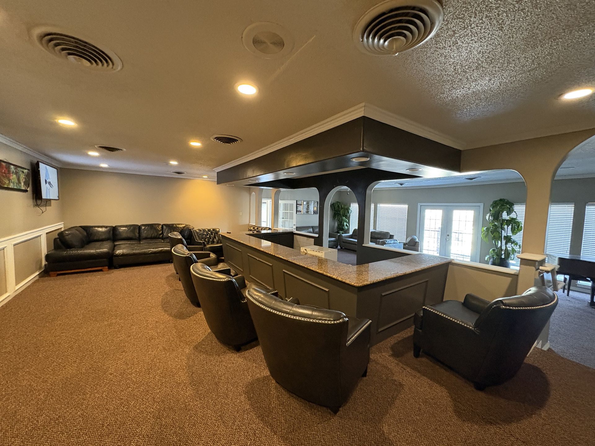 Interior bar with seating, a dark wooden counter, and a black leather sofa.