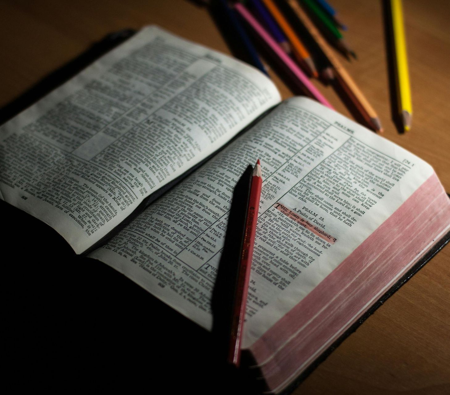 An open bible with a red pencil on it