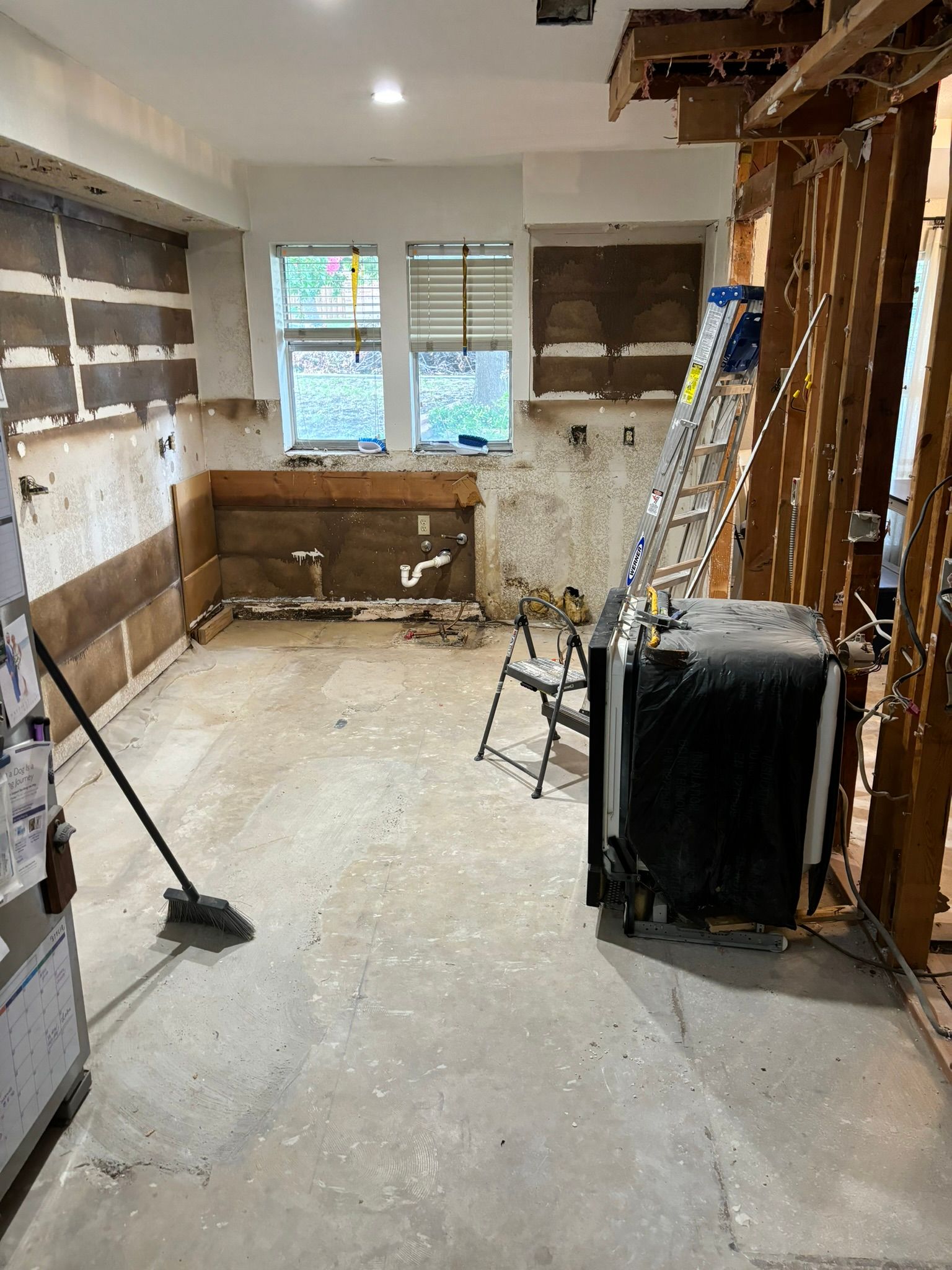 Creamy white kitchen with a black stove, stainless steel refrigerator, and granite countertops.